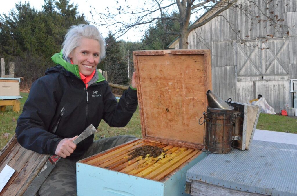 Sophie sur son terrain avec une ruche ouverte