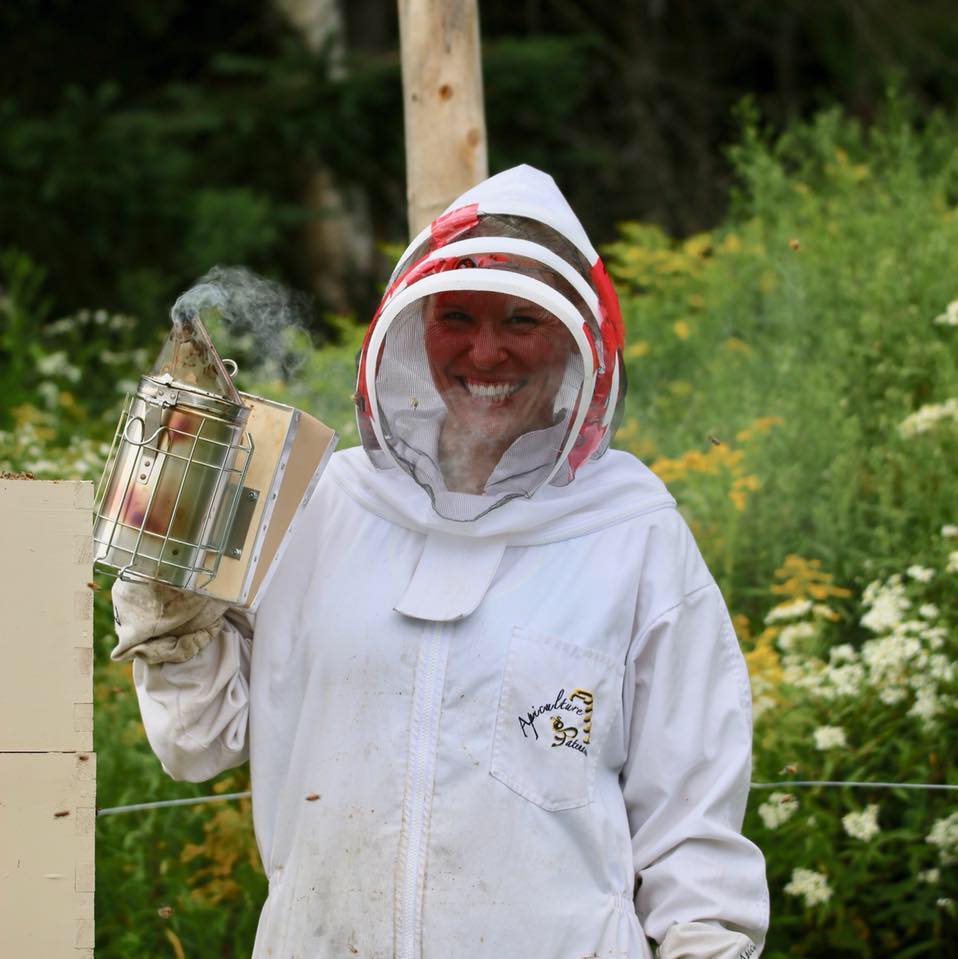 Sophie Roy dehors en tenue d'apicultrice.